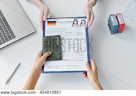 Top-down Shot Of Woman Applying For Travel Visa To Germany Giving Set Of Documents To Consular Offic