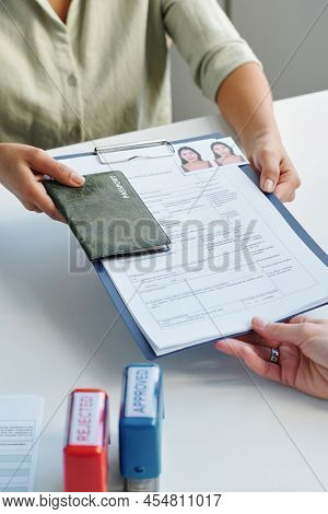 Vertical High Angle Of Unrecognizable Woman Applying For Work Visa Giving Set Of Documents To Consul
