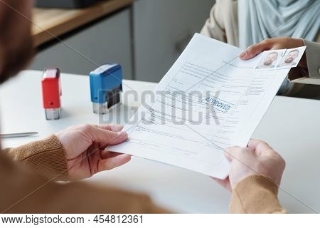 Unrecognizable Muslim Consular Officer Wearing Hijab Giving Documents Back To Man After Successful I