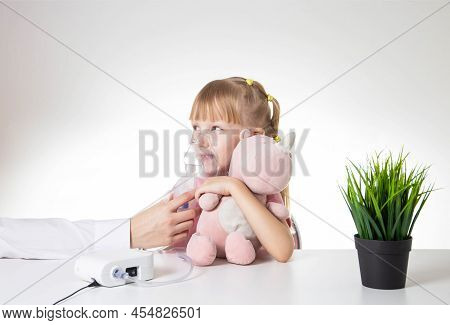 Beautiful Little Girl Breathing Into An Inhaler For Asthma And Pneumonia At Home. Treatment Of Disea