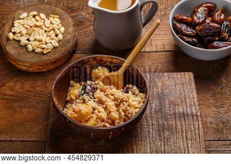 A Plate Of Couscous With Saffron And Nuts On A Wooden Table Next To Dates And Nuts. Save A Place. Ho