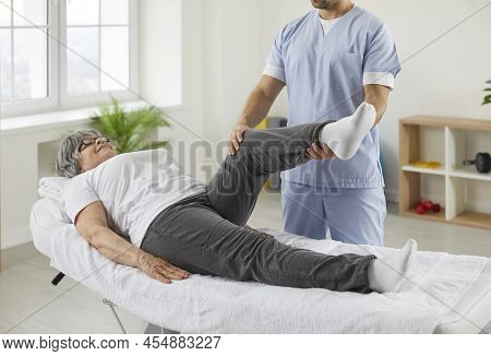 Chiropractor, Osteopath Or Physiotherapist Examining Leg And Knee Of Senior Woman