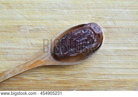 Organic Fresh Nutritious Dried Hurma Dates Medjool Grains, In Wooden Spoon On Cutting Board