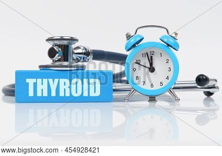 Medical Concept. On A White Surface There Is An Alarm Clock, A Stethoscope And A Blue Block With The