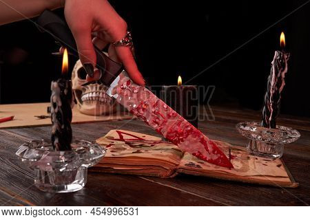 Antichrist Satanic Wiccy Blood Sacrifice Ritual Concept. Female Hand Holds Bloody Knife Close-up.