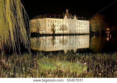 School building in the mirror of pond by night in Litovel, Czech Republic