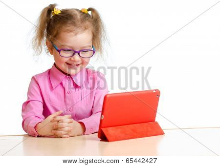 smiling kid in glasses looking at mini tablet pc screen sitting at table