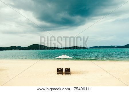 white sand beach resort with two sunbeds and umbrella