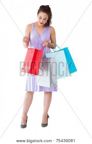 Stylish brunette in purpul dress opening shopping bag on white background