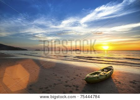 Tropical landscape. Canoe on the ocean beach during the amazing sunset.
