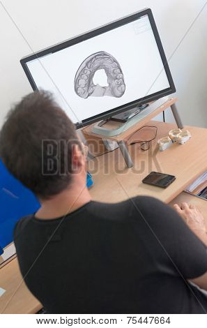 Worker in a dental lab pointing to computer screen