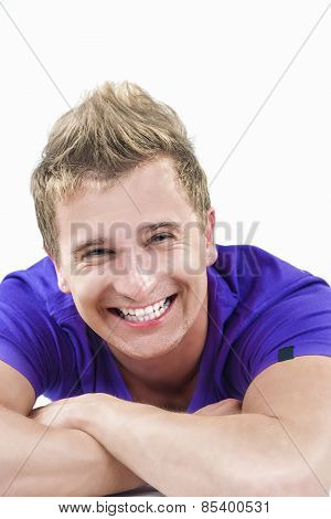Closeup Portrait Of Happy Smiling Young Caucasian Handsome Tanned Man Laying Down With Hands Folded