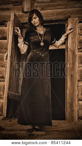 beautiful young woman with dark hair in a black velvet historical dress is standing at the door