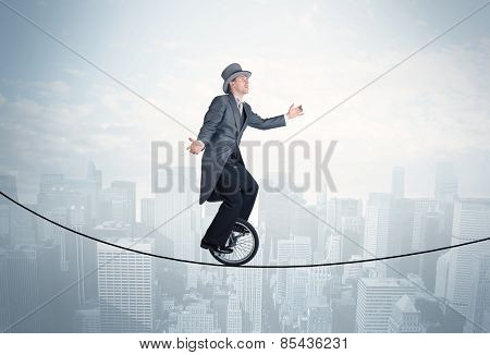 Brave guy riding a monocycle on a rope above cityscape concept