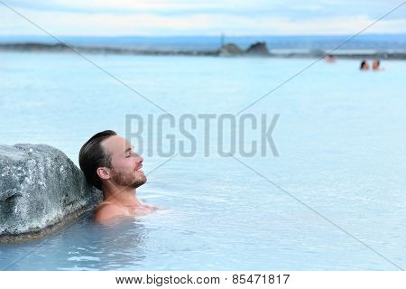 Geothermal spa. Man relaxing in hot spring pool on Iceland. Young man enjoying bathing relaxed in a blue water lagoon Icelandic tourist attraction.