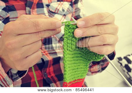 closeup of a young man knitting