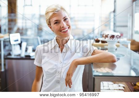 Selfassured female cook smiling in front of her bakery