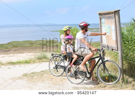 Family of three on a biking day looking at map