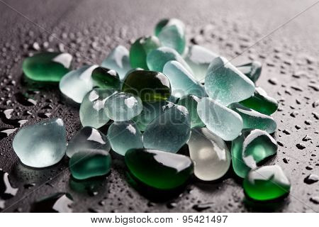 hip of wet glass pieces polished by the sea closeup on black background
