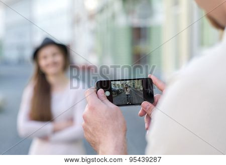 Touristic couple shooting on the modile phone at the city streets under sunlight.