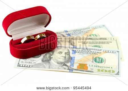 Wedding rings in box on banknotes, isolated on white background. Marriage of convenience