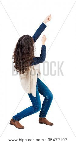 back view of standing woman pulling a rope from the top or cling to something.  Rear view people collection.   Isolated over white background. Girl in sheepskin jerkin pulling a rope from the top.
