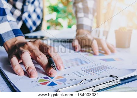 Business man hand working with business graph or analysis chart and using laptop computer .Close up business team analysis and strategy concept with sun flare.