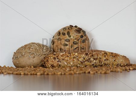 Three cereal delicious freshly baked baguettes with sunflower pumpkin sesame seeds and sprouted wheat grains around with white background.