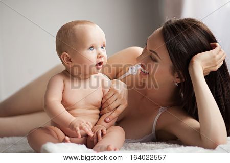 Young mother playing with her baby. She smiles and they are happy together.