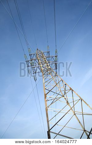 High-voltage power line grey metal prop with many wires vertical view over clear cloudless blue sky bottom-up view