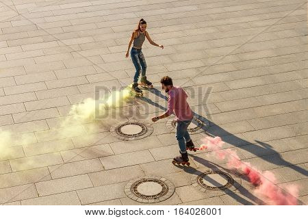 Couple is rollerskating. Colorful smoke coming from rollerskates. Colorize the world.