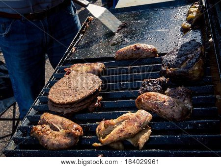 Chicken and hamburger on grill at feria de mataderos