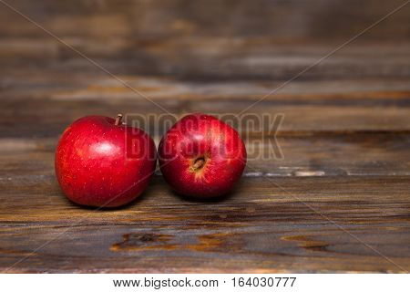 Two red ripe apples on a wooden background close up