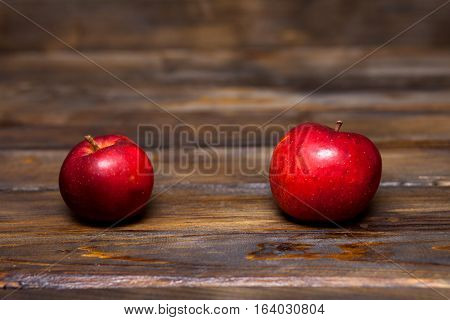 Two red ripe apples on a wooden background close up
