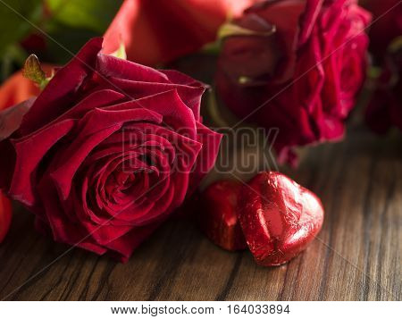 Chocolate hearts red roses bouquet with red ribbon on dark wooden table