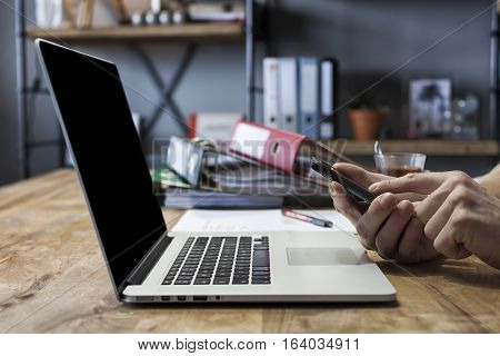 Man working at his home with laptop moblie phone and documents at the dinner table