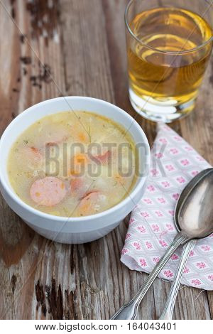 Healthy and warm soup: Barley soup with smoked sausage, carrots, celery, potatoes - your perfect winter soup on table with rye bread and apple juice