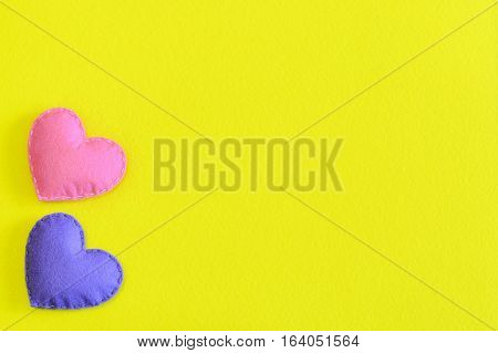 Two felt hearts isolated on yellow background with copy space for text. Valentine's day, wedding or mother's day background or card. Handmade felt hearts decorations. Top view