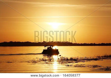 Group of people on a boat watching the sunset at the lake