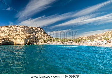Tourists relax and bath in crystal clear water of Matala in south of Creta. There are many caves near the beach.