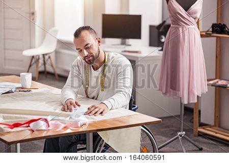 Seeking harmony. Demanding devoted focused dressmaker putting colorful bands against main cloth trying figuring out which color looking better