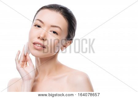 Facial cleansing. Joyful cute young woman holding a cotton pad and smiling while cleaning her skin