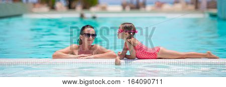 Mother and kid enjoying summer vacation in swimming pool