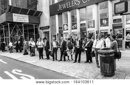 New York August 2 2016: People are lined up at a bus stop at the end of a work day near the Diamond District on 47th street.