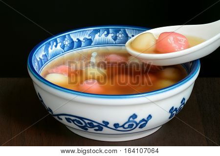 Bowl of sweet Chinese tangyuan dessert being eaten with a spoon