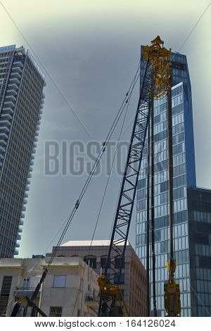 Crane and building under construction in Tel-Aviv. Industrial construction crane in Israel. Vintage Style Toned Picture