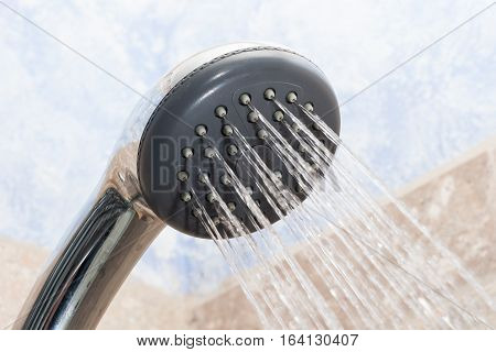 Chrome showerhead with water spraying out of it.