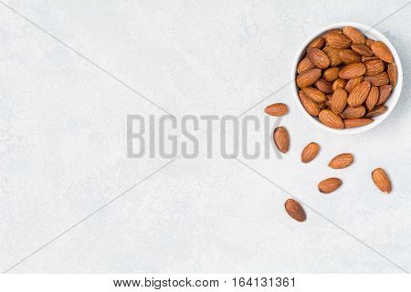 Almonds in bowl on bright background with copy space for text