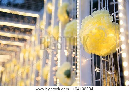 Close up of decoration yellow flowers decorated on white bower with defocused blurred lights bokeh background and copy space.
