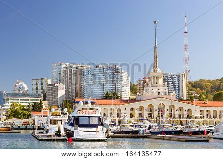 Sochi Russia - November 1 2015: View from water at Sochi sea port. Luxury yachts and private boats moored at pier. In background architecture modern resort town hotels and sanatoriums. Marine station complex Port. Krasnodarskiy kray Russia